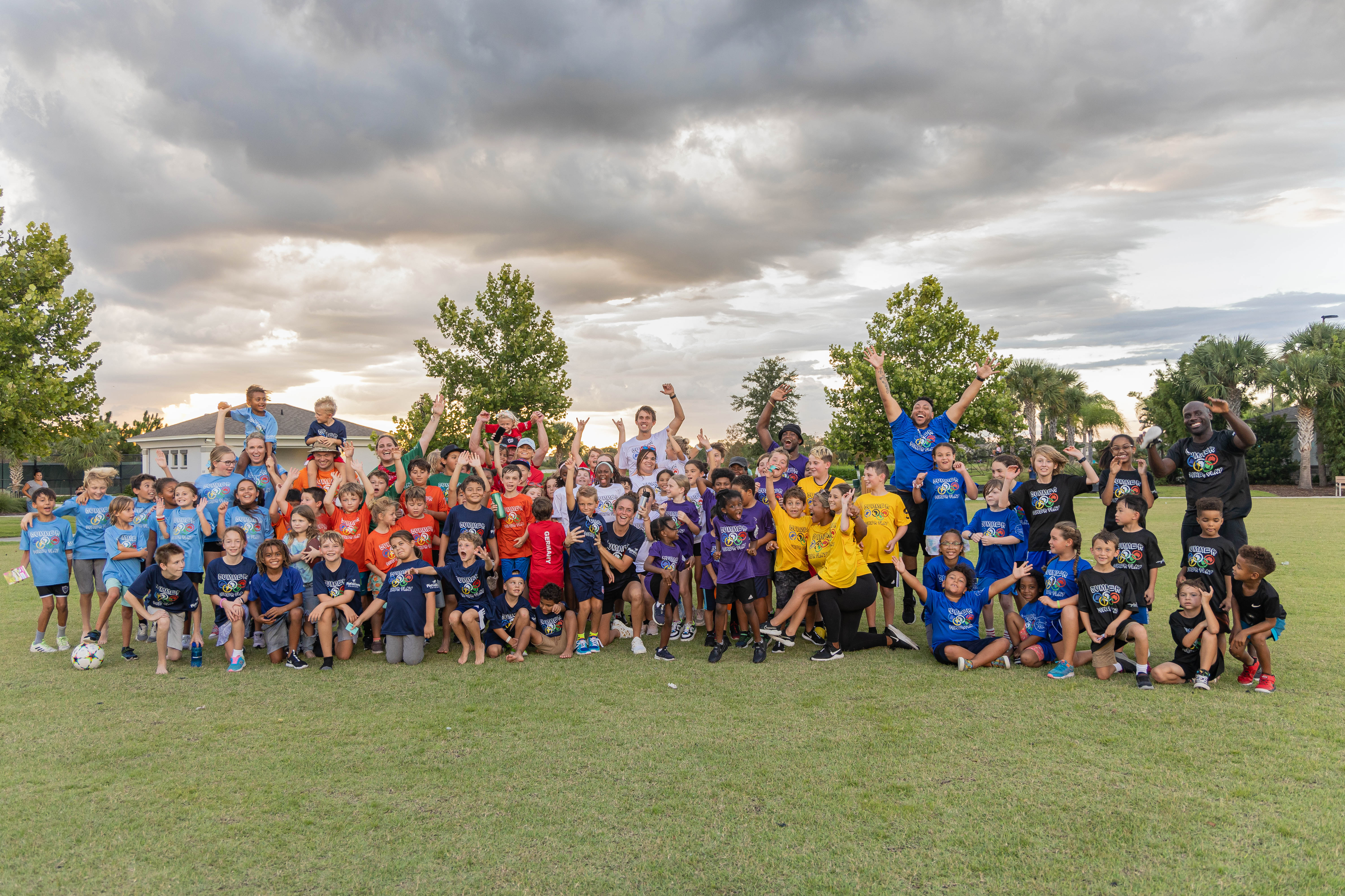 Summer Power Play 2024 group photo — campers and coaches cheering at sunset